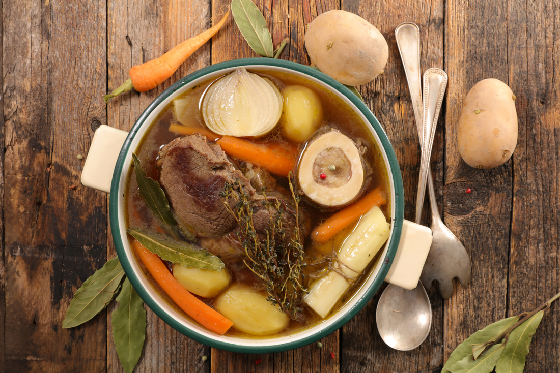 Pot Of Organic Ingredients For Healthy Homemade Bone Broth Recipe On Farmhouse Style Table