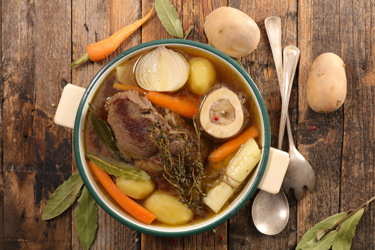 Pot Of Organic Ingredients For Healthy Homemade Bone Broth Recipe On Farmhouse Style Table
